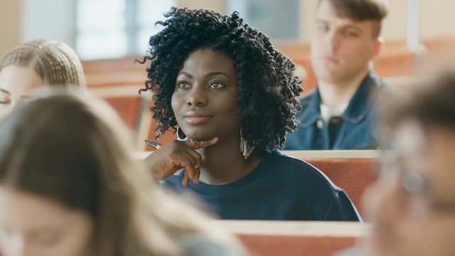 Smart and Beautiful Young Black Girl Listens to a Lecture in a Classroom Full of Multi Ethnic Students. Shallow Depth of Field. Shot on RED EPIC-W 8K Helium Cinema Camera.