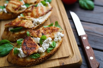 Italian restaurant menu, food background. Appetizing bruschetta with grilled chicken, ricotta and basil, delicious antipasti flat lay on wooden table, close up