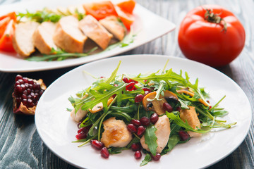 Diet food, proteins, healthy low-calorie meals concept. Chicken salad with pomegranate seeds and arugula and baked chicken breasts with zucchini and tomato slices