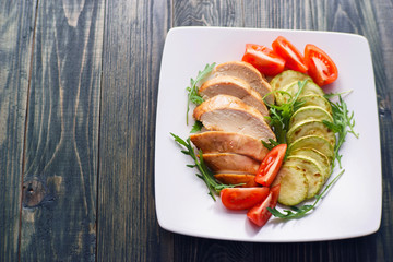 Dietary food, proteins, healthy low-calorie eating concept. Baked chicken breasts with zucchini, tomatoes and arugula flat lay with copy space. Healthy meals background, diet concept