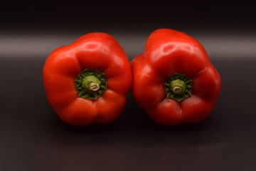 Tasty bright red peppers on a seamless black background. 