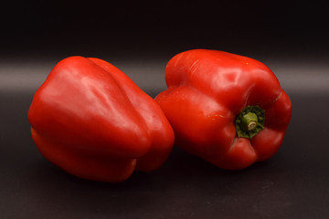 Tasty bright red peppers on a seamless black background. 