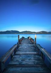 Wooden pier or jetty on a blue lake sunset and sky reflection on water. Versilia Tuscany, Italy