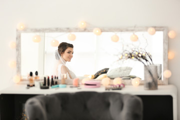 Reflection of beautiful young bride with makeup created by professional artist in mirror