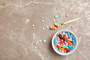 Bowl and different pills on color background