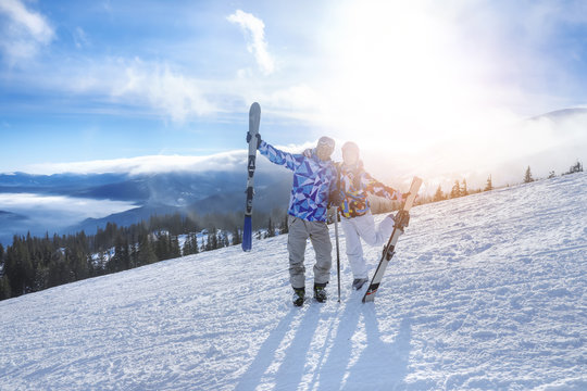 Happy couple on ski piste at snowy resort. Winter vacation