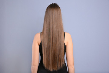 Fototapeta premium Young woman with long beautiful hair on grey background