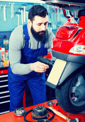 Smiling male worker fixing failed  motorcycle