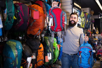 Obraz premium Young man customer examining backpacks in store