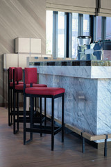 Fototapeta na wymiar Row of empty wooden chairs in front of marble counter bar