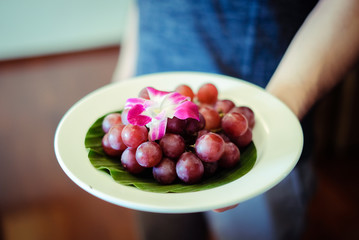 Red grape in dish with flower on top.
