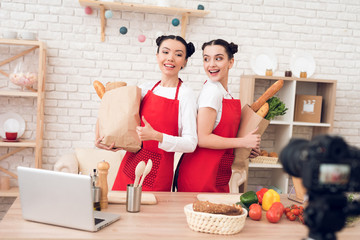 Two culinary bloggers hold up packagges with food to camera.