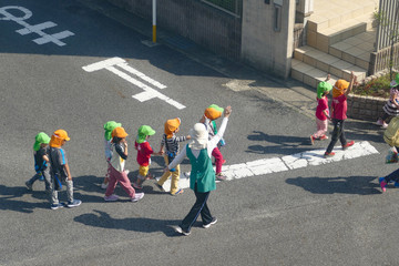 交差点を横断中の園児たちと保育士