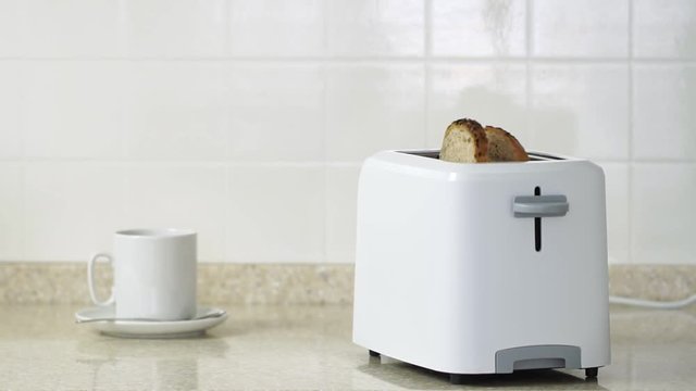 Roasted toast bread popping up from white modern toaster machine.