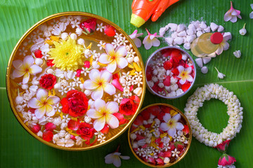 Thai traditional jasmine garland and Colorful flower in water bowls decorating and scented water, perfume, marly limestone, pipe gun on Banana leaf for Songkran Festival or Thai New Year