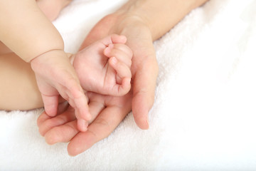 Obraz na płótnie Canvas 小さな赤ちゃんの手を母の手で包むイメージ