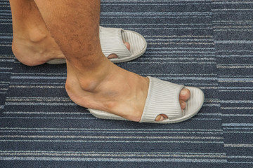 close up men wear too tight sandal on his feet in the house