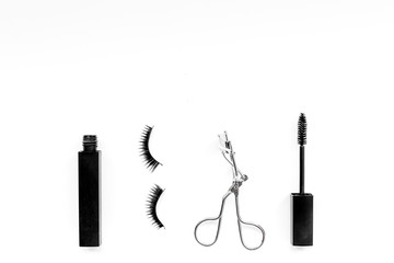 Cosmetics and tools for voluminous lashes. Mascara, false eyelashes, eyelash curler on white background top view space for text