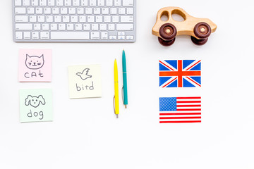 English for children. British and american flags, computer keyboard, stickers with vocabulary, toy on white background top view copy space