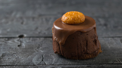 Fresh cake decorated with cookies on a dark wooden table.