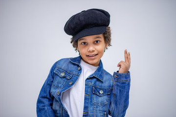 cute Lovely dark-skinned boy with age 6 years in different clothes shows different emotions on different backgrounds