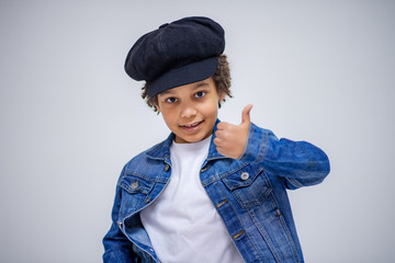 cute Lovely dark-skinned boy with age 6 years in different clothes shows different emotions on different backgrounds