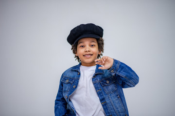 cute Lovely dark-skinned boy with age 6 years in different clothes shows different emotions on different backgrounds