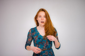 Cute beautiful red-haired girl shows different emotions in different poses on different background in different clothes