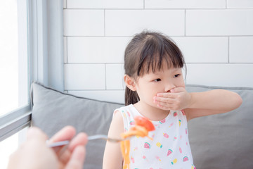 Little asian girl close her mouth by hand refuse to eat tomato in spaghetti