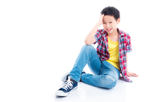 Young Asian Teenager Boy Sitting And Smiles Over White Background