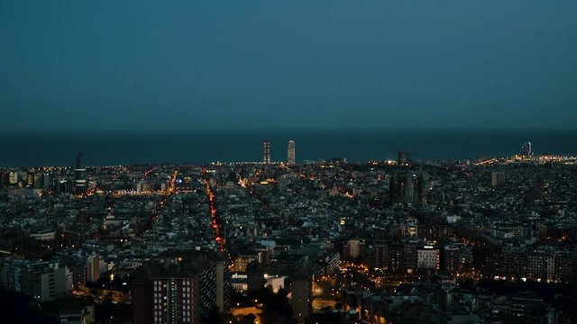 A time lapse of Barcelona, Spain from the evening to the night. It is sunset time and the sun is almost gone. The Mediterranean sea is at the back. The view is taken from the antiaircraft refugee.