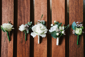 Fototapeta na wymiar Top view of wedding boutonniere for the groom and bridesmaids on wooden background, free space. Wedding details outdoor with copy space. Wedding morning preparation