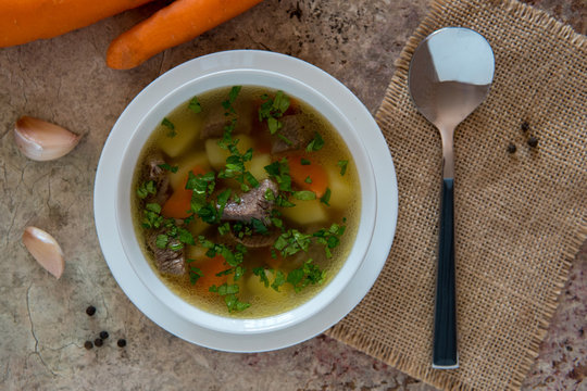 Soup with meat, potatoes and carrot. Beef soup in a white bowl