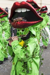 Basel carnival. Steinenberg, Basel, Switzerland - February 21st, 2018. Close-up of a carnival group in bright green costumes with red mouths on their masks.