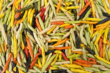 Background of bright colorful hand rolled dry pasta made from vegetables. Healthy vegetarian Italian pasta