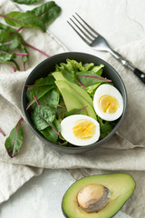 Healthy vegan food. Bowl with salad, avocado and egg, top view. Diet food concept.