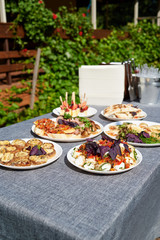 Delicious snacks, appetizers, sandwiches on party or picnic table. Holiday summer party table outdoor in garden. Catering banquet table with different food snacks on birthday or wedding celebration