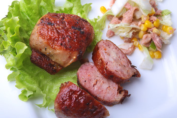 Marinated roaste chicken breasts cooked on BBQ and served with fresh salad on white plate, close-up.