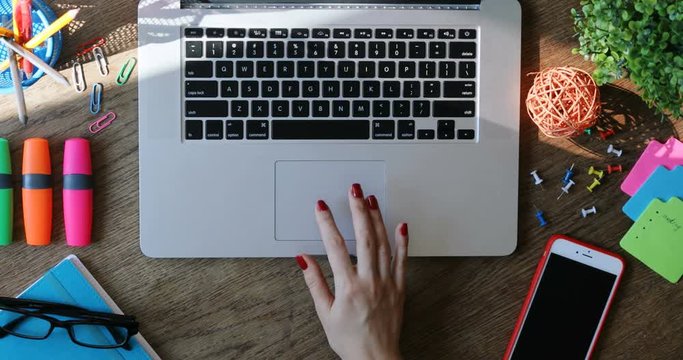 Woman hands using touchpad and typing on keyboard laptop close-up top view modern smartphone working art space desk internet searching online business creative innovation writing freelancer sunlight