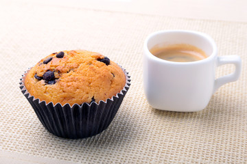 Perfect morning breakfast with Delicious homemade cupcakes with raisins, chocolate chips and espresso coffee in white cup on textile background. Muffins.
