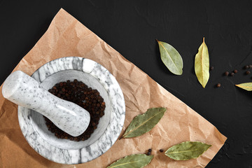 White mortar and pestle with dried peppers in flat lay on black background