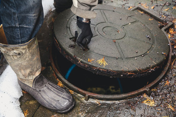 hand opens sewer hatch in yard