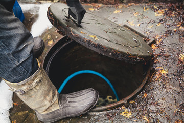 hand opens sewer hatch in yard