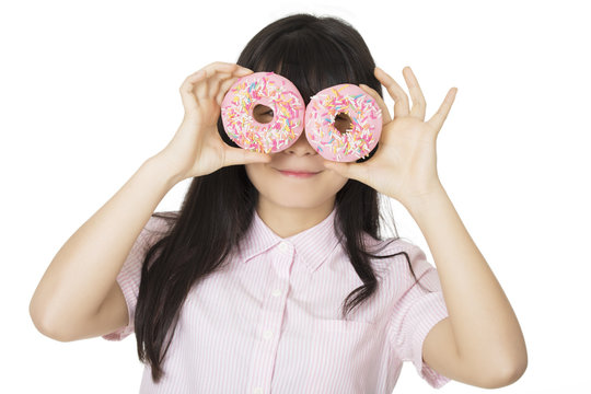Playful Asian woman having some fun with delicious strawberry frosted donuts