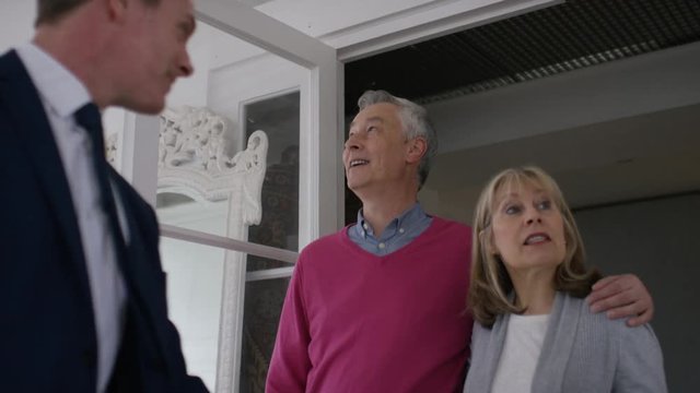 Mature couple viewing a property with a real estate agent, in slow motion