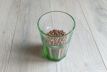 Lentils in a transparent green glass on a gray laminate