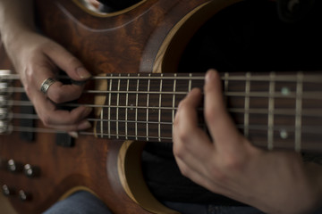 Obraz na płótnie Canvas Hands of rock musician playing the electric bass guitar
