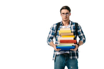 Fototapeta premium sad handsome student holding stack of books and looking at camera isolated on white
