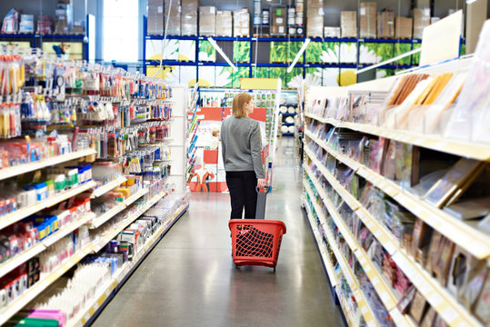Woman with basket on wheels in hypermarket
