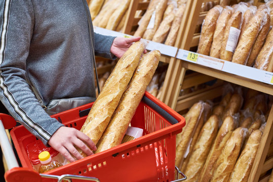 Buyer with baguettes in basket at store